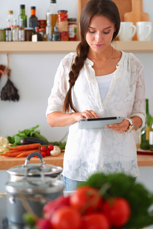 Young woman using a tablet computer to cook in her kitchenの写真素材
