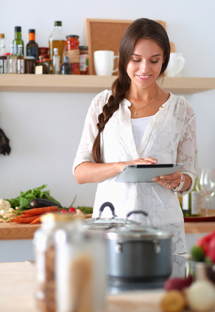 Young woman using a tablet computer to cook in her kitchenの写真素材