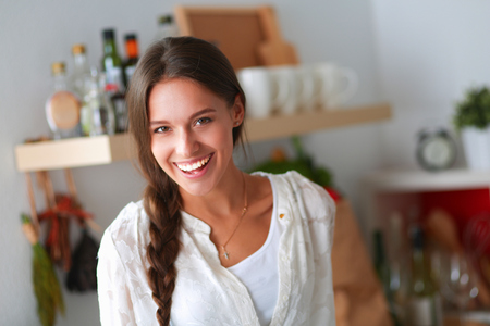 Young woman standing near desk in the kitchenの写真素材