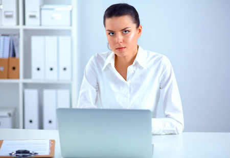 Young woman sitting at office table with laptopの写真素材