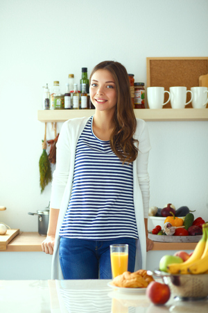Young woman standing near desk in the kitchenの写真素材