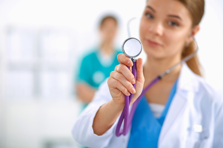 Young female doctor listening stethoscope standing in hospitalの写真素材