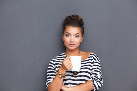 Portrait of young woman with cup tea or coffeeの写真素材
