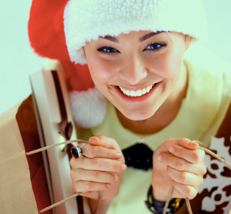 Smiling woman in santa hat with many gift boxes on white backgroundの写真素材