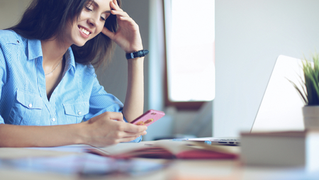 Young woman sitting at office table with laptopの写真素材