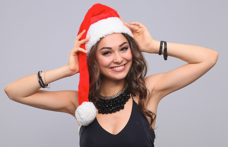 Attractive smiling woman in Santa Cap. Isolated over a gray background.の写真素材