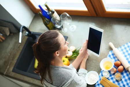 Woman baking at home following recipe on a tabletの写真素材