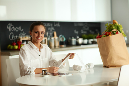 Young woman planning expenses and paying bills on her kitchenの写真素材