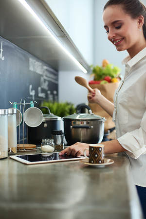 Young woman standing by the stove in the kitchenの写真素材