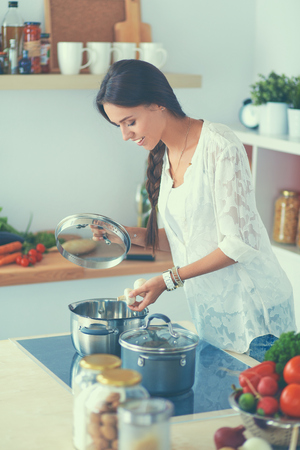 Young woman standing by the stove in the kitchenの写真素材