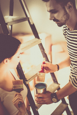 Portrait happy smiling young couple painting interior wall of new houseの写真素材