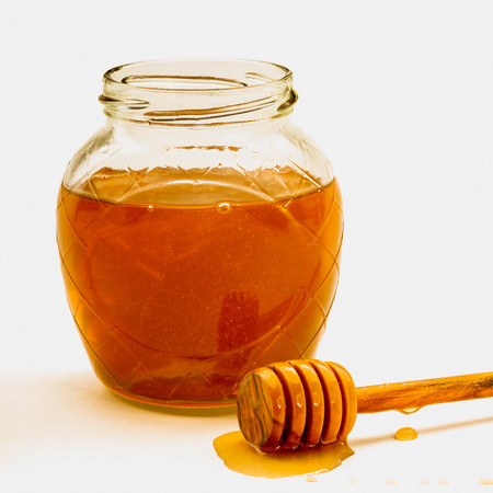 Glass jar full of honey wooden dipperの写真素材