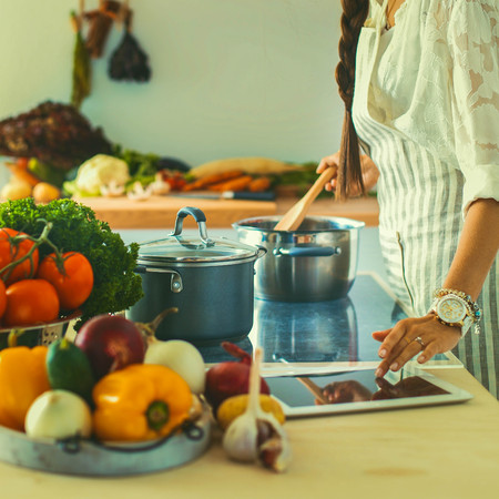 Young woman using a tablet computer to cook in her kitchenの写真素材