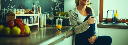 Young woman sitting a table in the kitchen .の写真素材