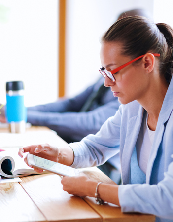Business woman sitting in her office using a tablet computerの写真素材
