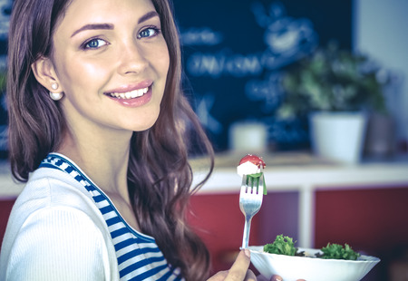 Young woman eating salad and holding a mixed saladの写真素材