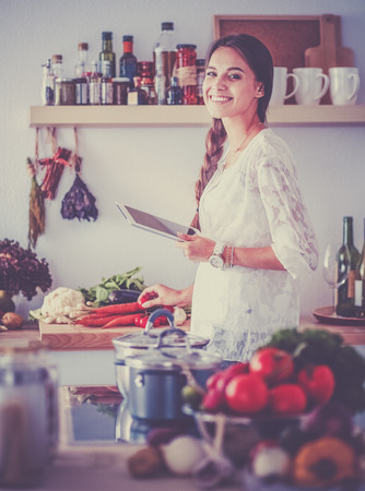 Young woman using a tablet computer to cook in her kitchenの写真素材