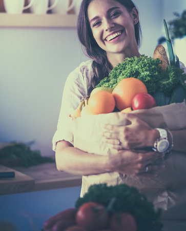 Young woman holding grocery shopping bag with vegetables and fruitの写真素材