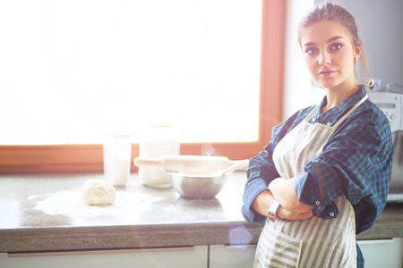 Beautiful woman cooking cake in kitchen standing near deskの写真素材