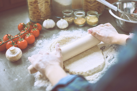 Beautiful woman cooking cake in kitchen standing near desk.の写真素材