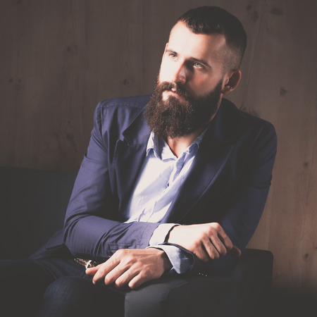 Businessman sitting the sofa in office lobby, isolated on dark backgroundの写真素材
