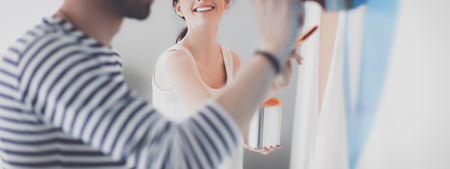 Portrait of happy smiling young couple  painting interior wall of new house.の写真素材