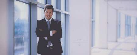 Portrait of businessman standing near window in officeの写真素材