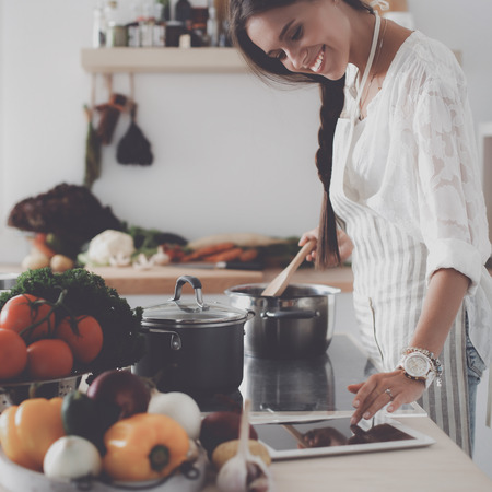 Young woman using a tablet computer to cook in her kitchenの写真素材