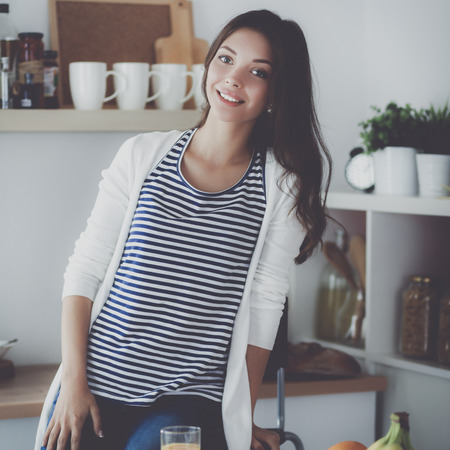 Young woman sitting near desk in the kitchenの写真素材
