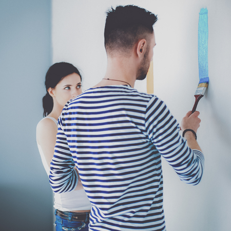 Portrait happy smiling young couple painting interior wall of new houseの写真素材