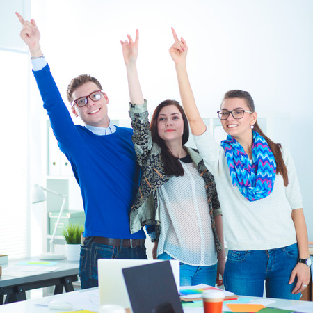 Young business people standing at office near desk and pointing upの写真素材