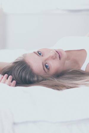 Pretty woman lying down on her bed at homeの写真素材