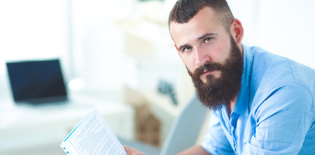 Young businessman sitting on chair with book in officeの写真素材