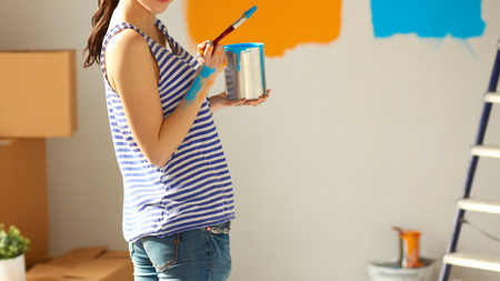 Happy smiling woman painting interior wall of new houseの写真素材