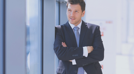 Portrait of businessman standing near window in officeの写真素材
