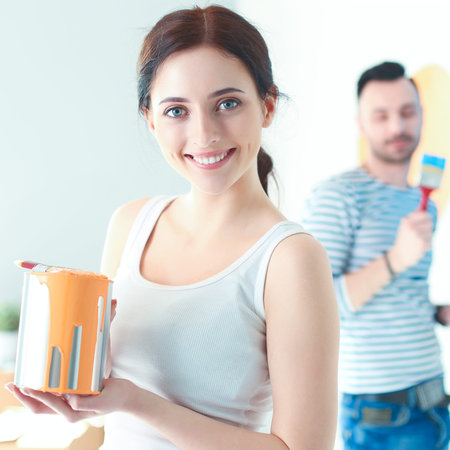 Portrait happy smiling young couple painting interior wall of new house