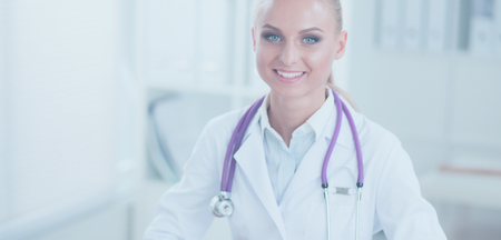 Beautiful young smiling female doctor sitting at the desk and writing.の写真素材