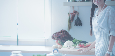Young woman standing near desk in the kitchenの写真素材