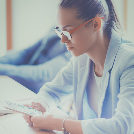 Business woman sitting in her office using a tablet computerの写真素材