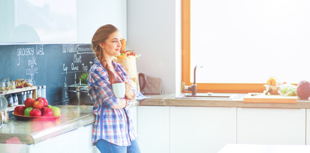 Happy woman drinking tea in the kitchen at homeの写真素材