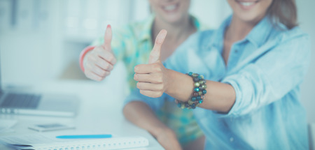 Two women working together at office, sitting on the deskの写真素材
