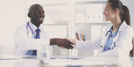 Two happy smiling young medical people handshaking at officeの写真素材