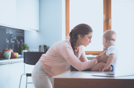 Mother with her baby in the bright kitchen at homeの写真素材