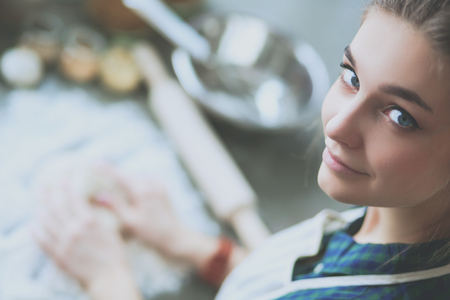 Beautiful woman cooking cake in kitchen standing near deskの写真素材