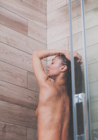 Young beautiful woman under shower in bathroomの写真素材