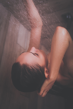 Young beautiful woman under shower in bathroomの写真素材
