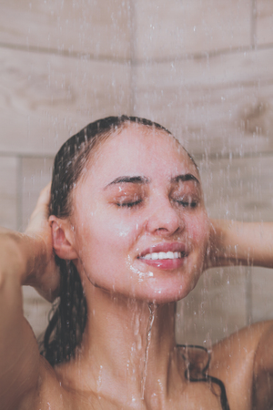Young beautiful woman under shower in bathroomの写真素材