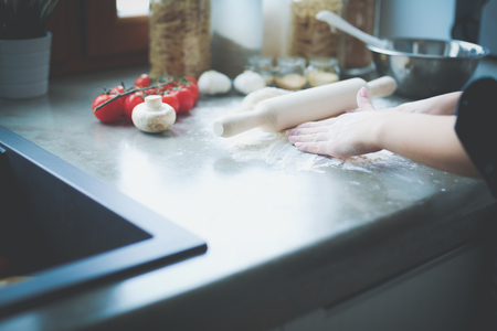 Beautiful woman cooking cake in kitchen standing near deskの写真素材