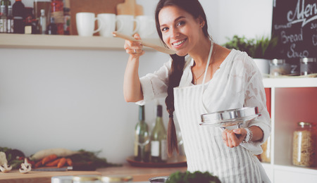 Cooking woman in kitchen with wooden spoonの写真素材