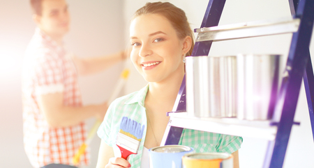 Portrait happy smiling young couple painting interior wall of new houseの写真素材